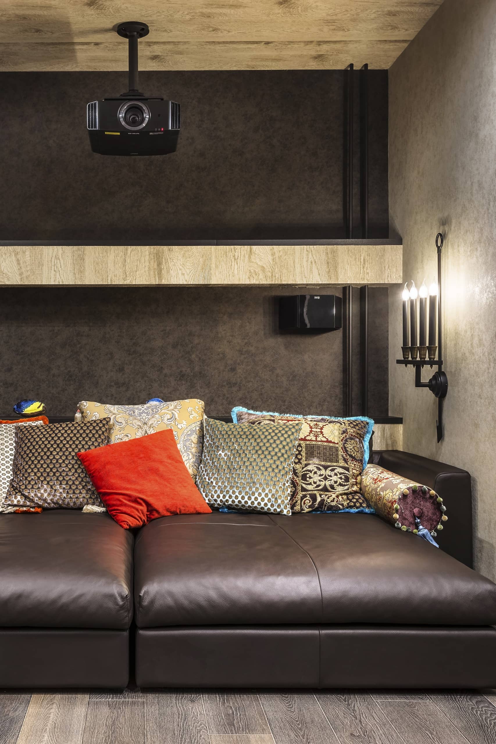 Разноцветные подушки на тёмном диване из кожи